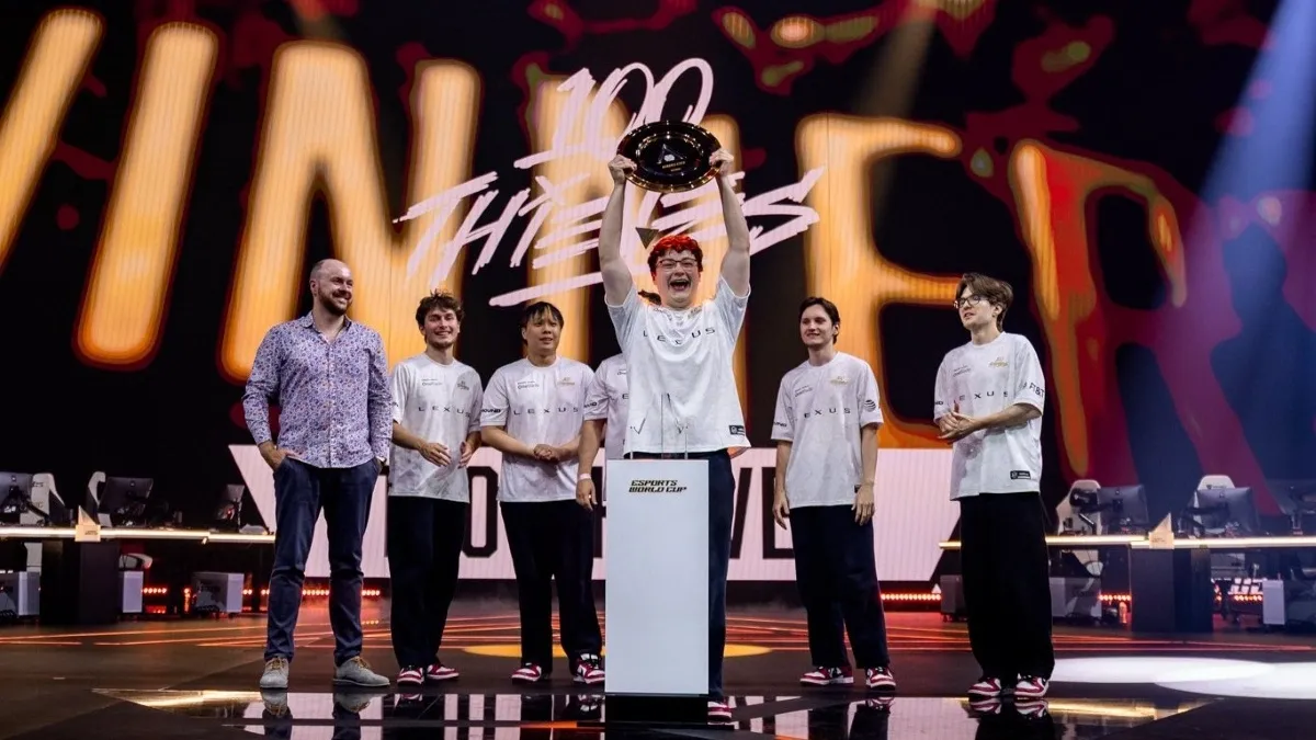 An image of 100 Thieves' VALORANT roster raising the VALORANT Esports World Cup 2026 trophy.