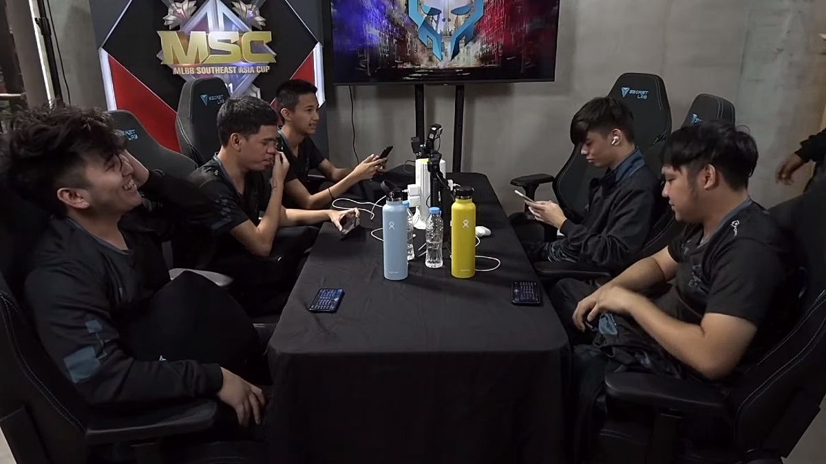 Execration MLBB team sitting around a table post game
